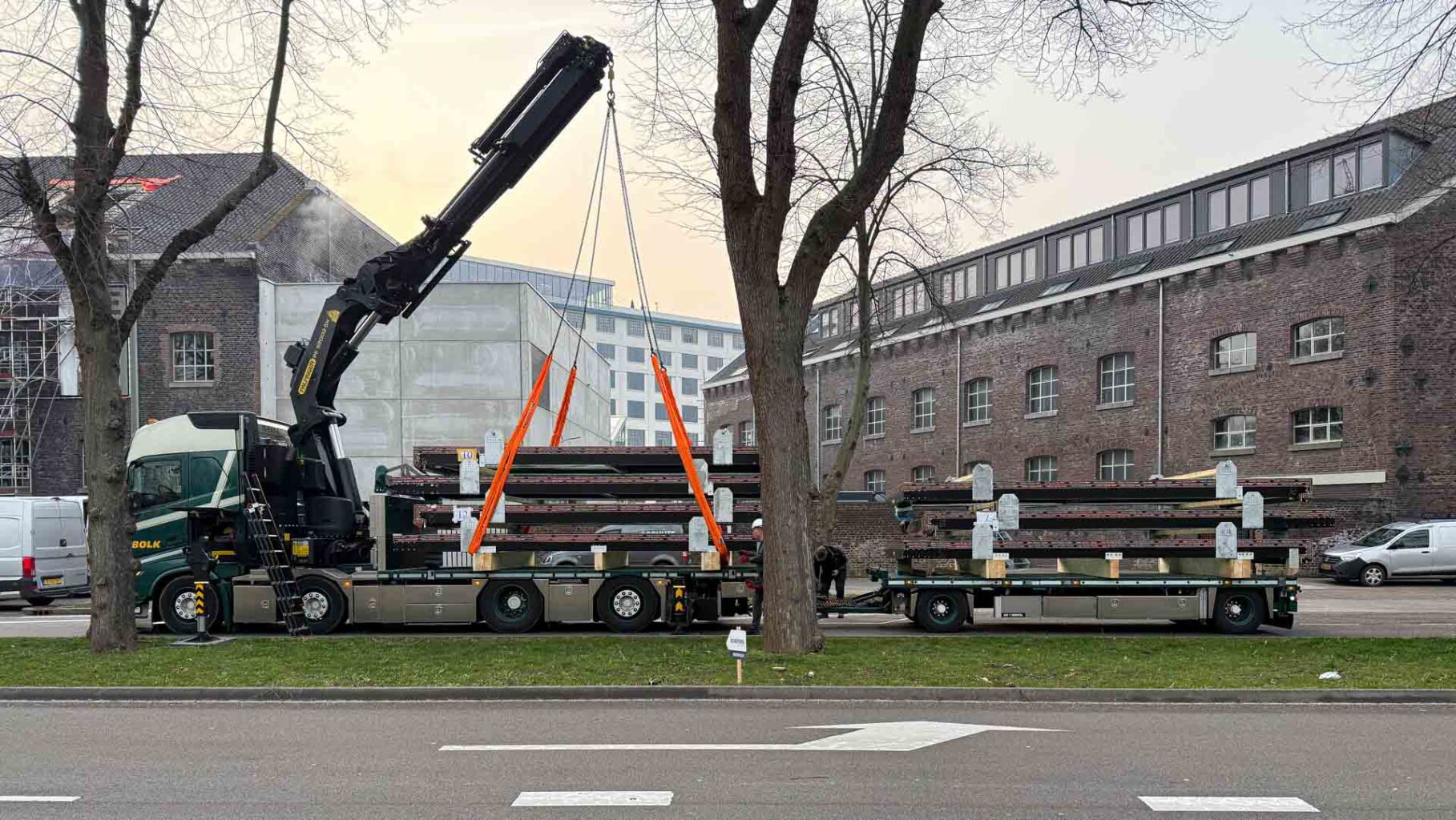 Modern sliding roof windows for the historic Sphinxkwartier: the first 7 windows have been installed! 1 The image shows the loading of the OpenAir 2-part sliding roof windows for the construction project in the Sphinxkwartier. A heavy-duty crane lifts the secured window frames from the truck to prepare them for safe transport to the construction site. In the background, the historic industrial architecture underscores the successful blend of old and new.